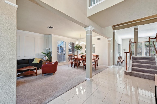interior space with stairway, ornamental molding, light carpet, decorative columns, and light tile patterned flooring