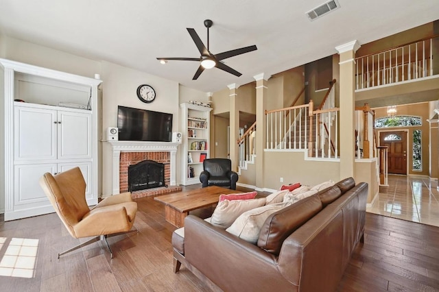 8320 Pommel Dr, Austin, TX 78759 - living area featuring ceiling fan, stairs, a brick fireplace, wood-type flooring, and decorative columns