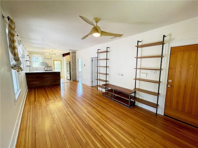 unfurnished living room featuring baseboards, light wood-type flooring, and ceiling fan