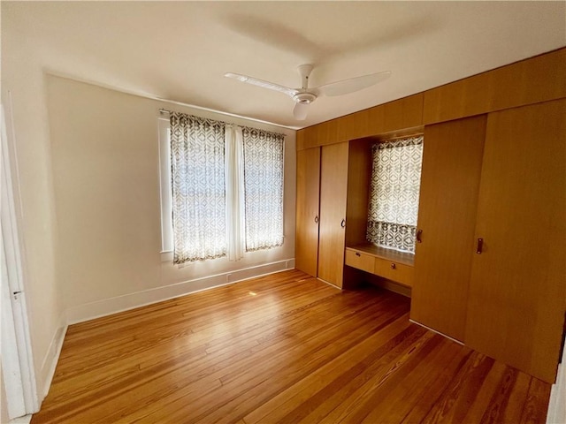 unfurnished bedroom featuring baseboards, multiple windows, light wood-style floors, and ceiling fan