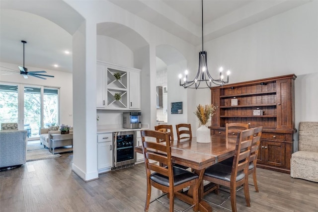 22306 Cape Travis Bnd, Lago Vista, TX 78645 - dining area featuring beverage cooler, ceiling fan with notable chandelier, wood finished floors, arched walkways, and a high ceiling