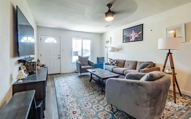 living area featuring visible vents, baseboards, a ceiling fan, and wood finished floors