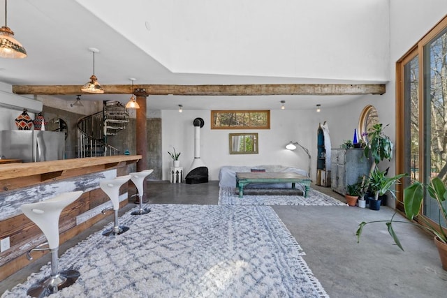 interior space featuring stairway, beam ceiling, concrete floors, and a wood stove