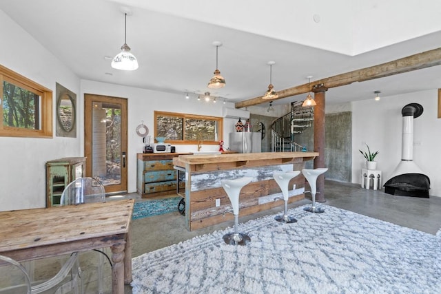 kitchen featuring pendant lighting, finished concrete flooring, freestanding refrigerator, and a wood stove