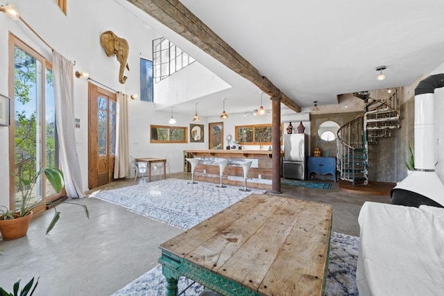 living room with beamed ceiling, concrete floors, and stairway