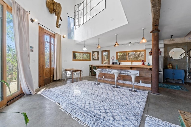 dining space featuring concrete flooring and a towering ceiling