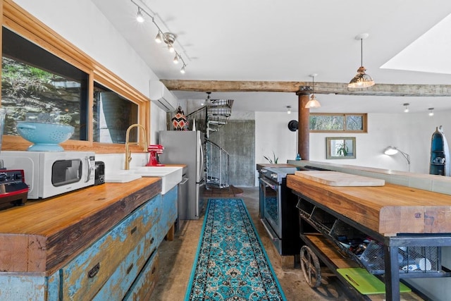 kitchen featuring beamed ceiling, track lighting, a wall unit AC, stainless steel appliances, and concrete flooring