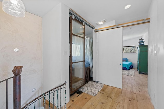 hall featuring visible vents, a barn door, and hardwood / wood-style flooring