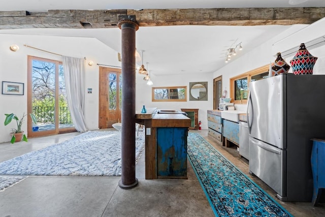 kitchen featuring dishwashing machine, concrete flooring, and freestanding refrigerator