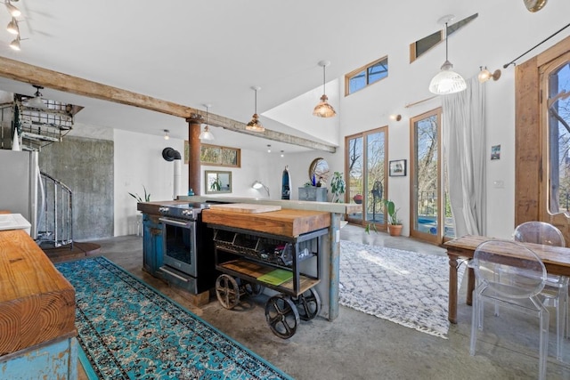 kitchen with pendant lighting, open floor plan, stainless steel appliances, concrete flooring, and a towering ceiling