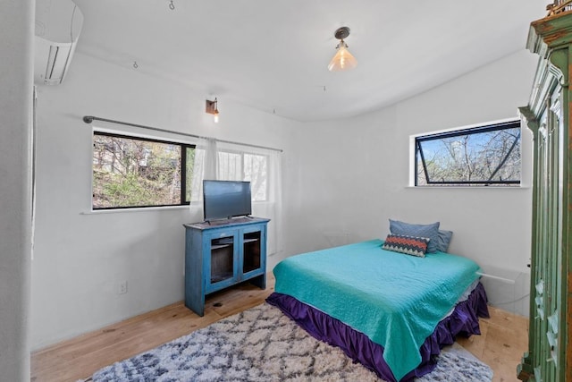 bedroom with a wall mounted air conditioner and wood finished floors