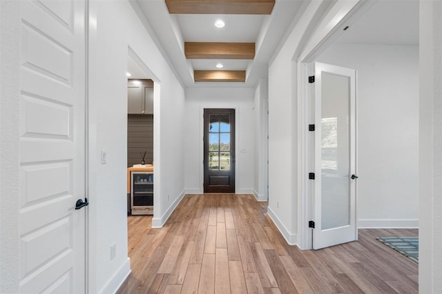 foyer featuring baseboards, beam ceiling, beverage cooler, and light wood finished floors