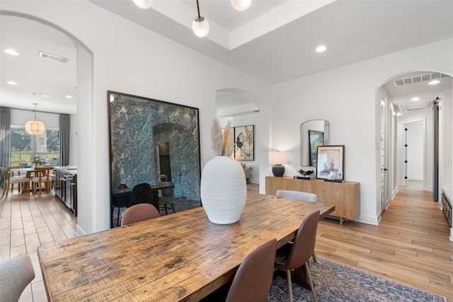 dining area with visible vents, baseboards, light wood-style flooring, recessed lighting, and arched walkways