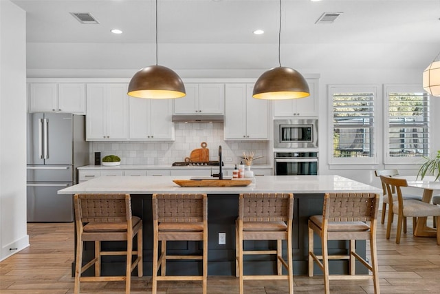 kitchen featuring tasteful backsplash, visible vents, under cabinet range hood, and stainless steel appliances