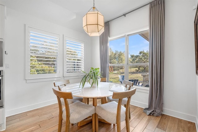 dining space with baseboards, plenty of natural light, and light wood-style flooring