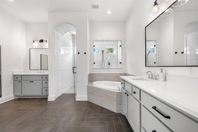 full bathroom with a sink, visible vents, a bath, and a tile shower