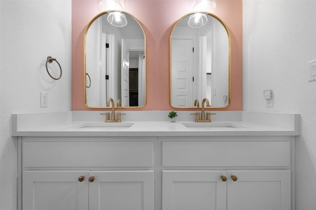 bathroom with double vanity, a textured wall, and a sink