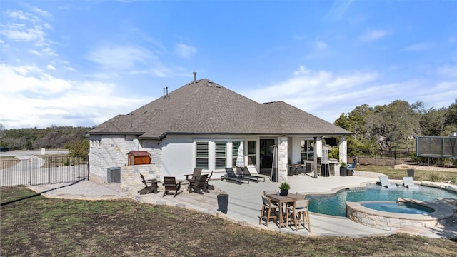 back of property featuring a patio area, stone siding, a trampoline, and fence