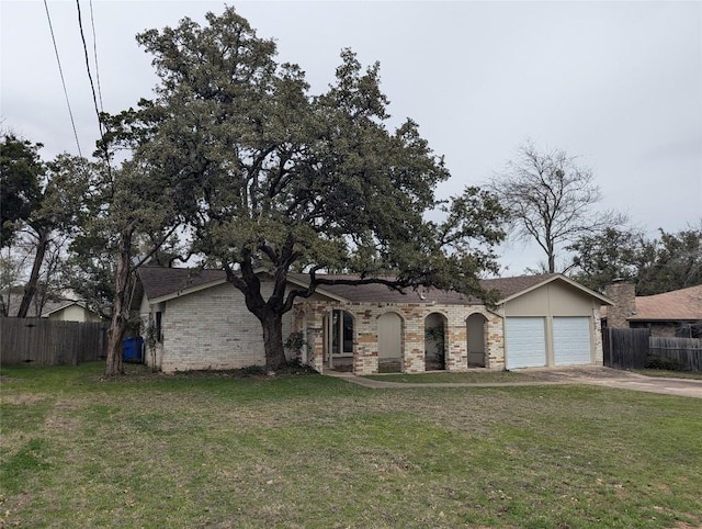 view of front of house with an attached garage, concrete driveway, a front lawn, and fence