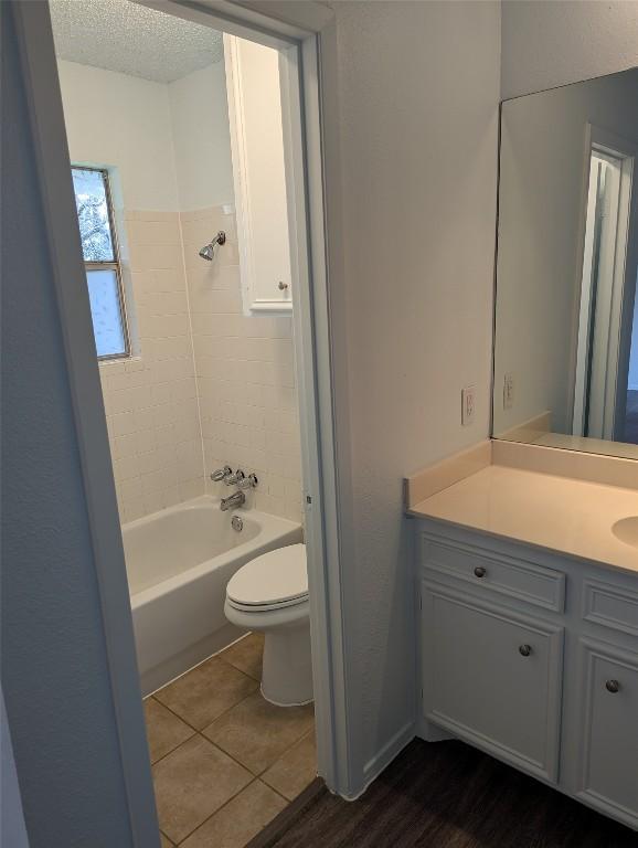 full bath featuring tile patterned floors, toilet, a textured ceiling, shower / bathing tub combination, and vanity