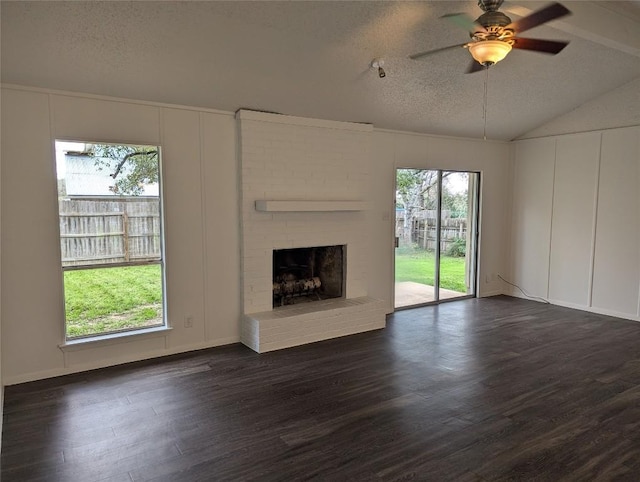 unfurnished living room featuring lofted ceiling, a decorative wall, a textured ceiling, a ceiling fan, and dark wood-style flooring