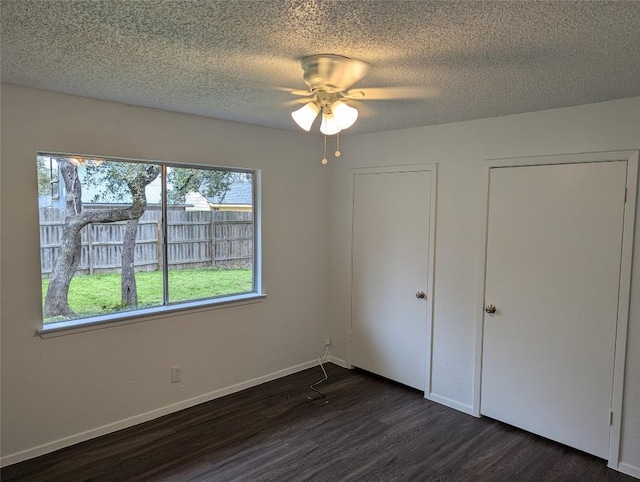 unfurnished bedroom with baseboards, a textured ceiling, dark wood finished floors, and a ceiling fan