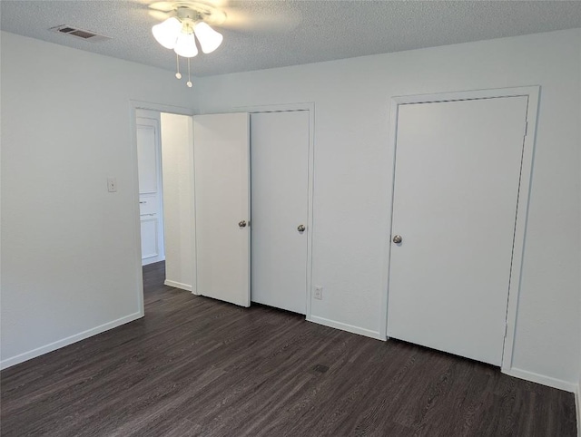 unfurnished bedroom with visible vents, baseboards, dark wood-type flooring, and a textured ceiling