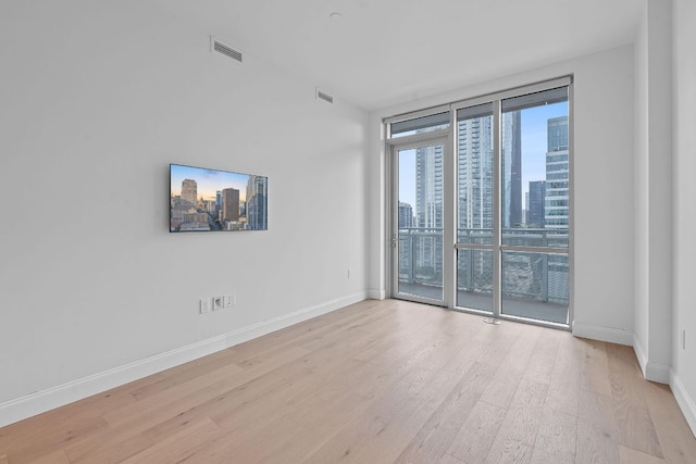 222 W Ave Unit 2109, Austin, TX 78701 - spare room featuring a skyline view, light wood finished floors, and baseboards
