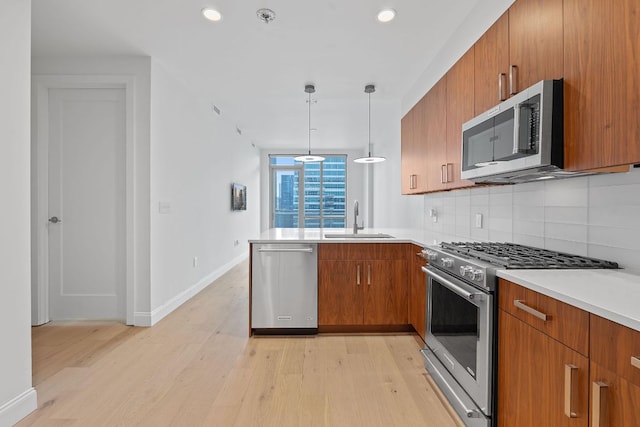 222 W Ave Unit 2109, Austin, TX 78701 - kitchen with stainless steel appliances, a sink, brown cabinetry, light wood-style flooring, and recessed lighting