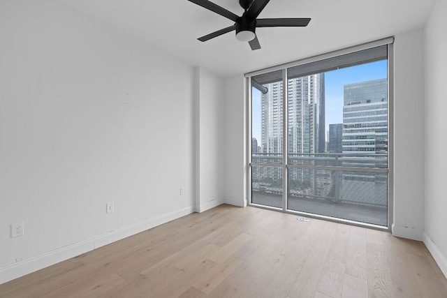222 W Ave Unit 2109, Austin, TX 78701 - empty room featuring expansive windows, ceiling fan, wood finished floors, a skyline view, and baseboards