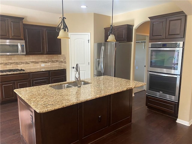 kitchen with a sink, stainless steel appliances, tasteful backsplash, and dark wood-style flooring