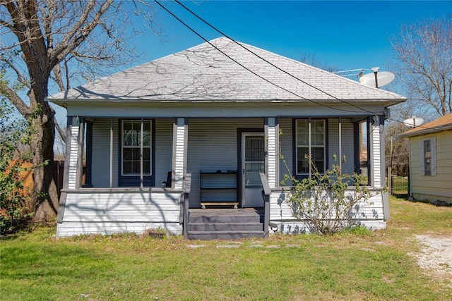 bungalow with a front yard, covered porch, and roof with shingles