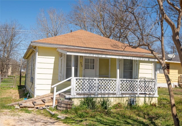 bungalow with fence, covered porch, and a shingled roof