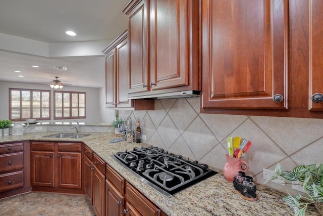 214 Apache Mountain Ln, Georgetown, TX 78633 - kitchen with light stone countertops, under cabinet range hood, tasteful backsplash, a sink, and black gas stovetop