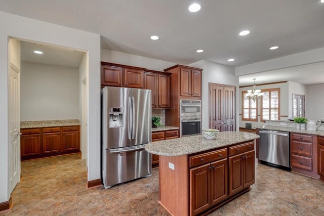 214 Apache Mountain Ln, Georgetown, TX 78633 - kitchen with a kitchen island, appliances with stainless steel finishes, light stone counters, a notable chandelier, and recessed lighting