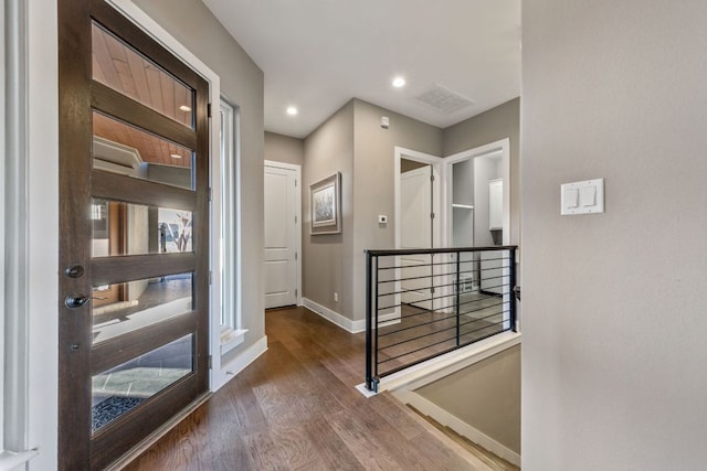 corridor with wood finished floors, baseboards, visible vents, recessed lighting, and an upstairs landing