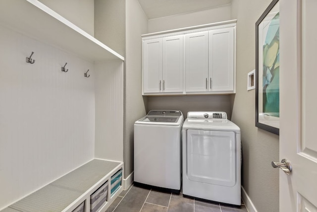 laundry room featuring tile patterned floors, baseboards, cabinet space, and washer and clothes dryer