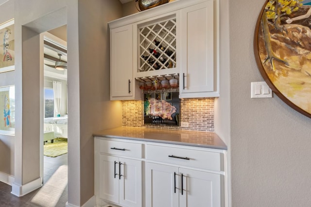 bar featuring tasteful backsplash, a bar, and baseboards