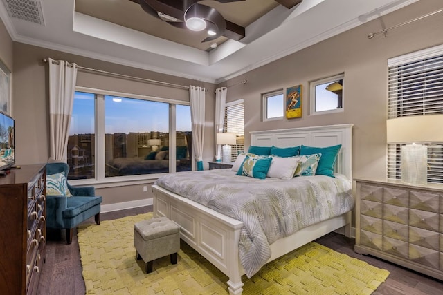 bedroom featuring a tray ceiling, visible vents, ornamental molding, and a ceiling fan