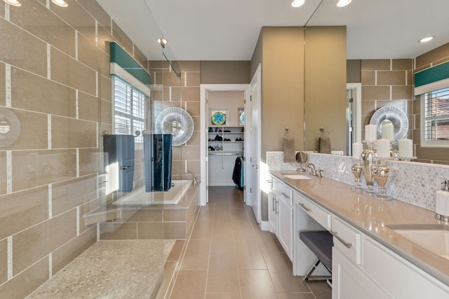 bathroom featuring tile patterned floors, a sink, tasteful backsplash, tile walls, and walk in shower