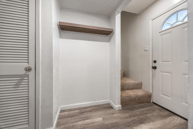 entryway featuring baseboards, a textured ceiling, wood finished floors, and stairs