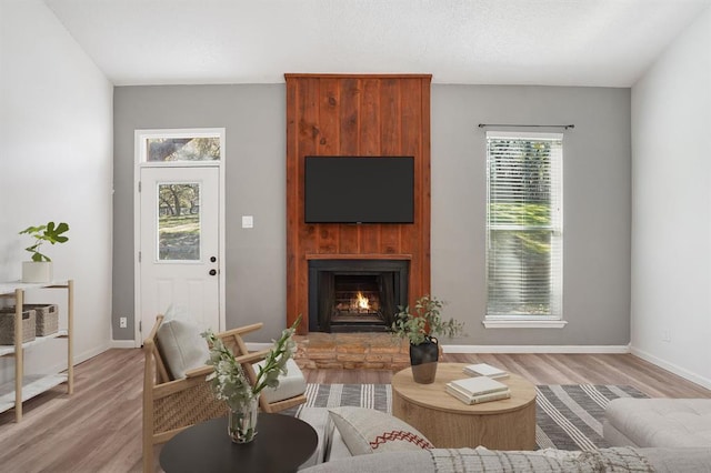 living room with light wood-style floors, baseboards, and a large fireplace