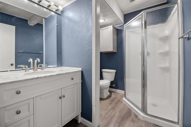 bathroom with wood finished floors, toilet, a stall shower, and vanity