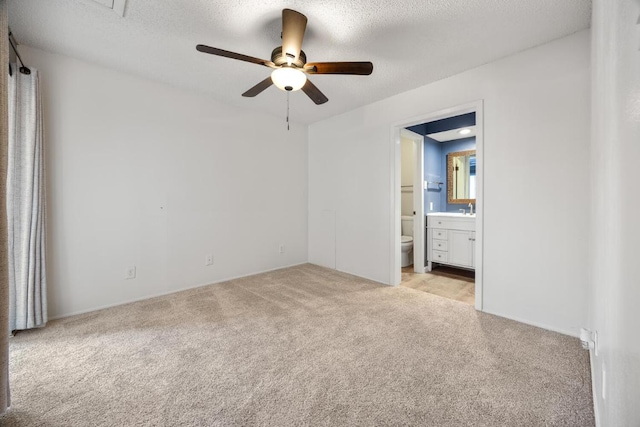 unfurnished bedroom with light carpet, a textured ceiling, ensuite bath, and ceiling fan