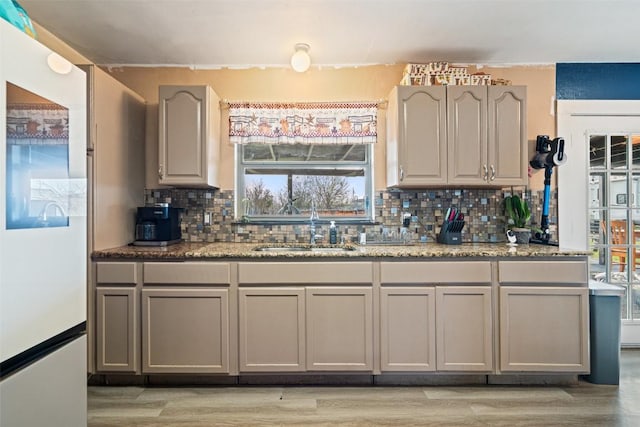 10505 Ruidosa St, Austin, TX 78719 - kitchen featuring backsplash, light wood-type flooring, gray cabinets, freestanding refrigerator, and a sink