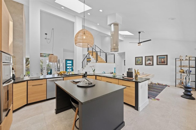 203 Golf Crest Ln, Lakeway, TX 78734 - kitchen with a skylight, stainless steel appliances, dark countertops, a peninsula, and a kitchen island