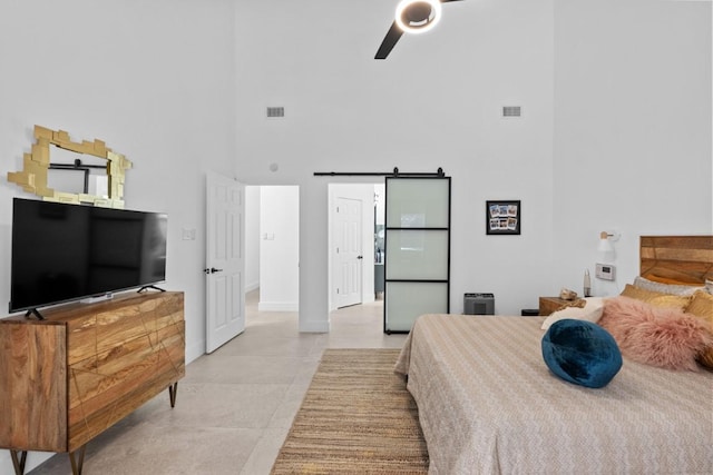 203 Golf Crest Ln, Lakeway, TX 78734 - bedroom with a high ceiling, a barn door, a ceiling fan, baseboards, and light tile patterned floors