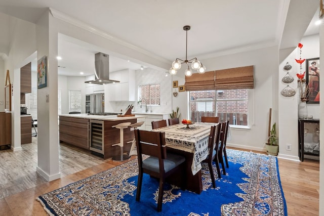 10914 Sierra Oaks, Austin, TX 78759 - dining space featuring wine cooler, light wood-style flooring, crown molding, baseboards, and a chandelier
