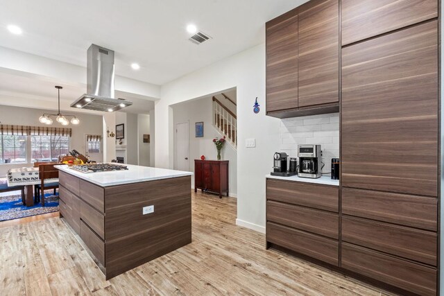 10914 Sierra Oaks, Austin, TX 78759 - kitchen featuring island range hood, stainless steel gas cooktop, light wood-style floors, light countertops, and modern cabinets