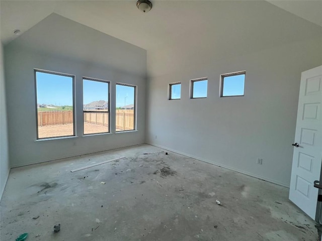spare room with baseboards and lofted ceiling
